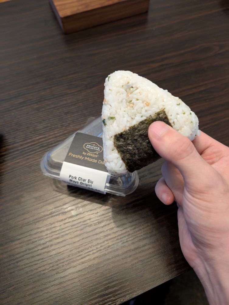 Holding an onigiri, the packaging on the table