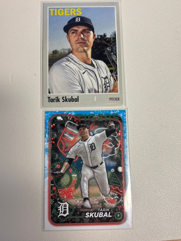 Two baseball cards of the Detroit Tigers picture Tarik Skubal.  The top one has a light gray border around a photo of him in a blue hat woth a white, old English D and white jersey with the same D in blue.  

The second card is a holiday themed card with Christmas related graphics around a photo of him pitching.
