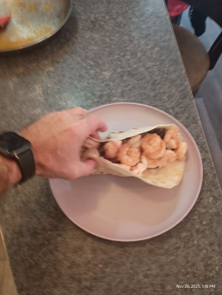 Soft taco with like 30 jumbo shrimp and some hairy veiny guy's hand holding it. 