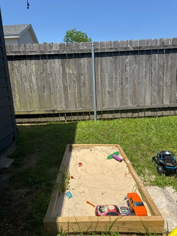 Yard sandbox with toys with a clear blue sky 