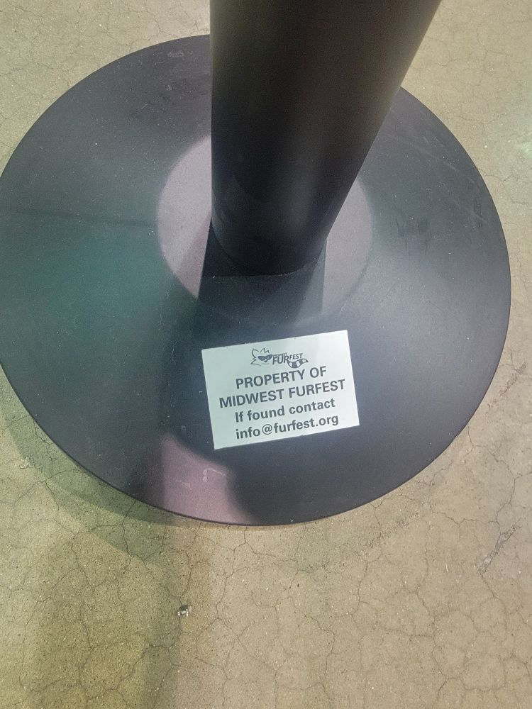 A path marker with a card that says. "PROPERTY OF MIDWEST FURFEST if found contact info@furfest.org
