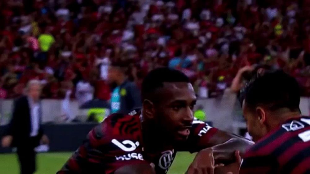 a group of soccer players are celebrating a goal on a field sponsored by adidas .