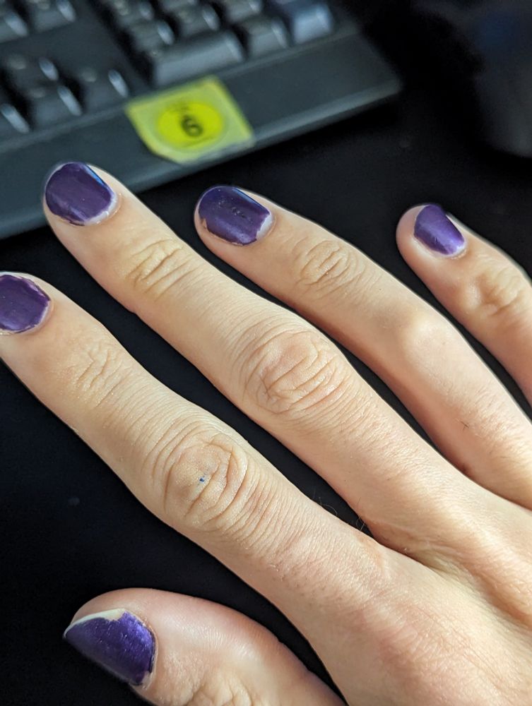 Eine Hand mit lilafarbenen Fingernägel