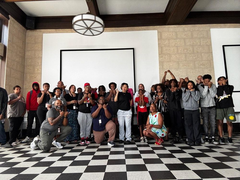 Group photo of Durham County staff and Project BUILD participants inside the Justice Resources Center. Many are holding up hands in celebration.