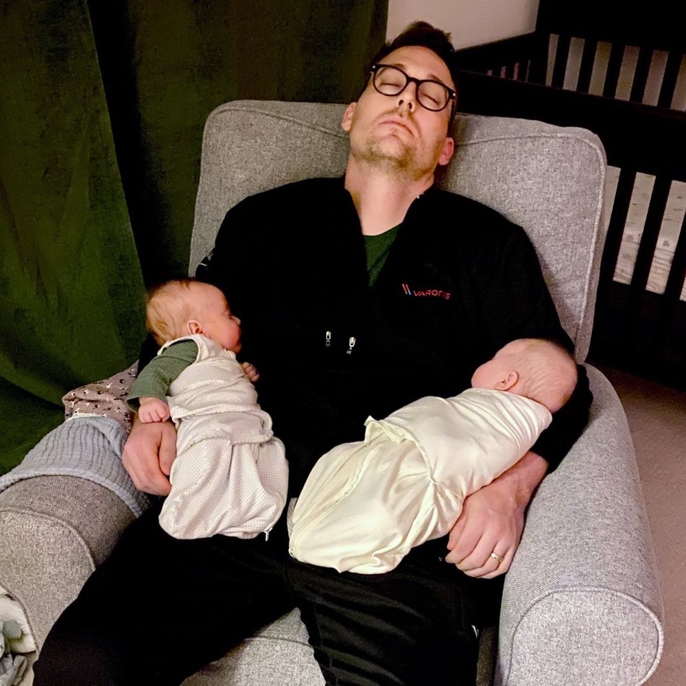Aaron asleep with newborn twins on his lap.