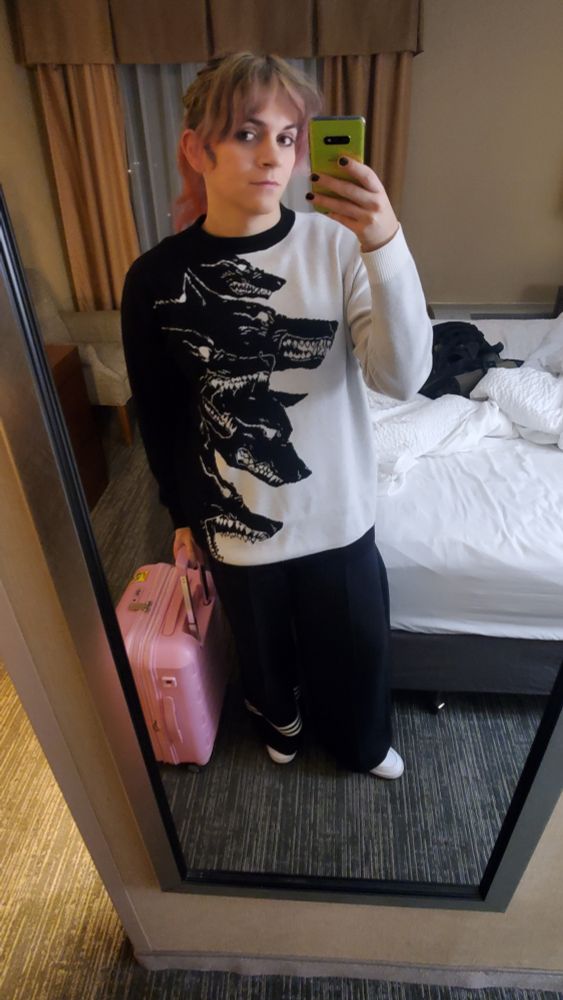 Black and white contrast sweater with barking wolf heads, wide leg high waist pleated Adidas sweats, white Adidas high tops, pink suitcase to match the pink ends of my hair. 