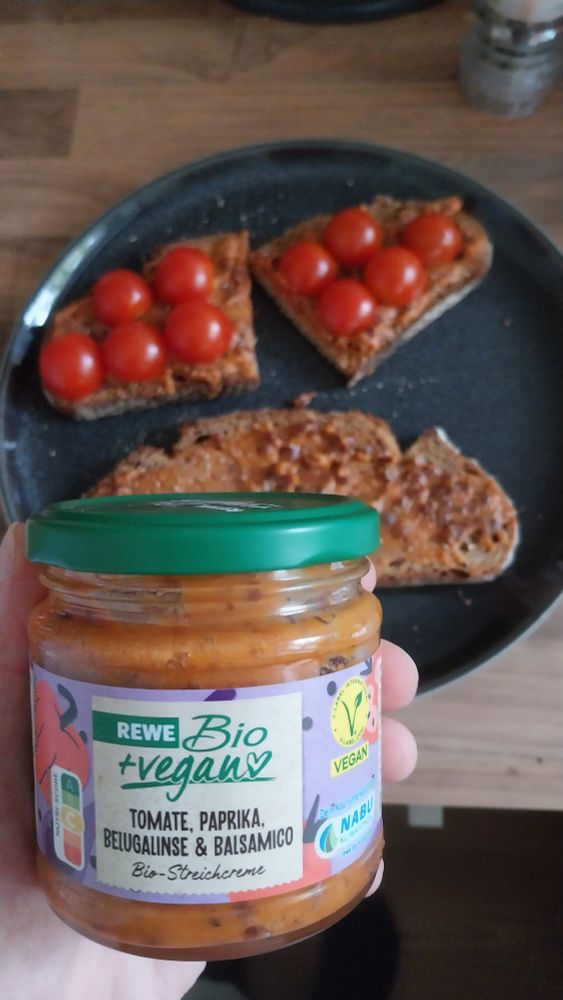 REWE Bio+vegan Tomate Paprika Belugalinse & Balsamico Bio-Streichcreme
im hintergrund zwei scheiben brot bestrichen mit dem aufstrich, eine davon mit tomaten drauf