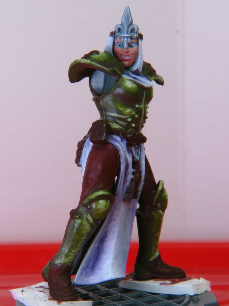 A warhammer 40000 miniature showcase. It's a work in progress. A novitiate with a shocked and concerned look is reluctantly staring at something in the distance while timidly striking a battle stance.