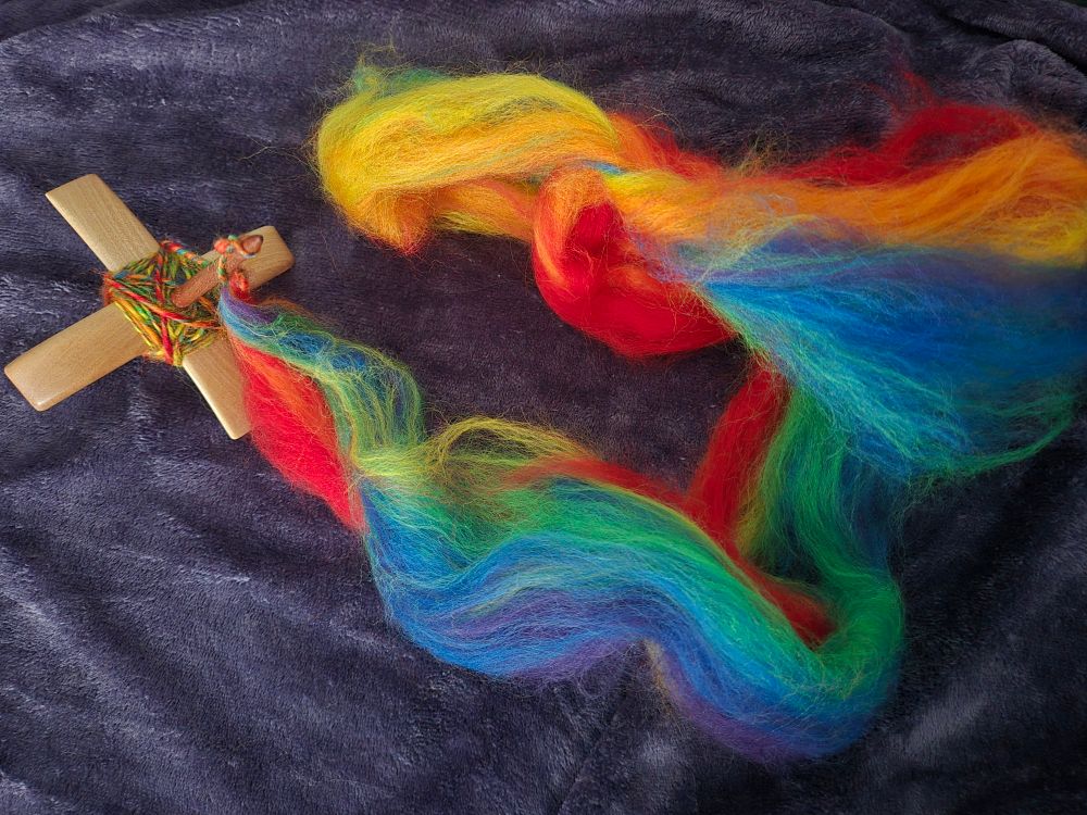 Small Turkish Spindle with multi colored yarn wound on it, which leads to roaving of rainbow colors. 