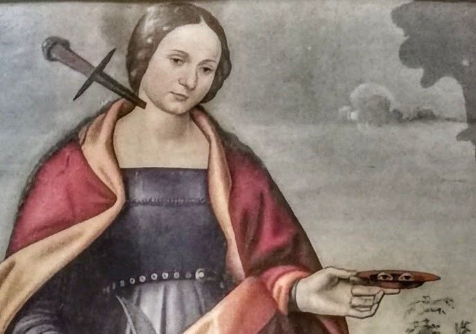 A lady with dagger on her neck carrying eyes on a plate