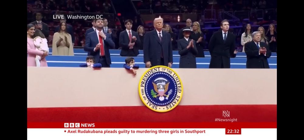 President Donald Trump and his family sit at a long bank of seating at a rally.