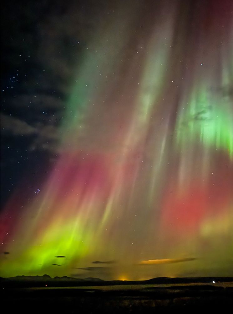 Green, purple, red, and yellow aurora over a highway in Iceland. 