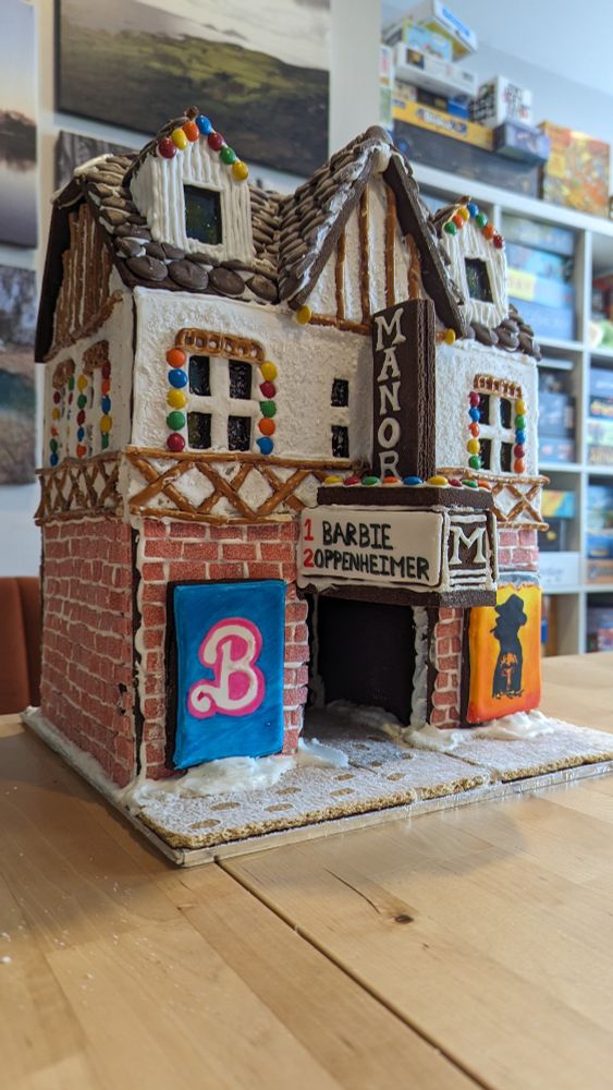 Gingerbread house of a movie theater playing the movies Barbie and Oppenheimer. The theater sign says "Manor."