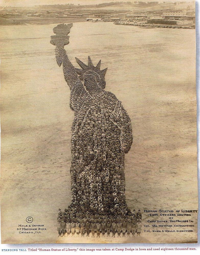b&w photograph taken from a tower showing 18,000 men positioned in a field to create the shape of the Statue of Liberty