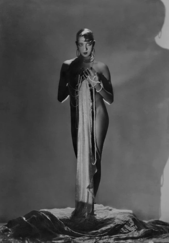 Black and white photograph of Baker holding a dress up in front of herself