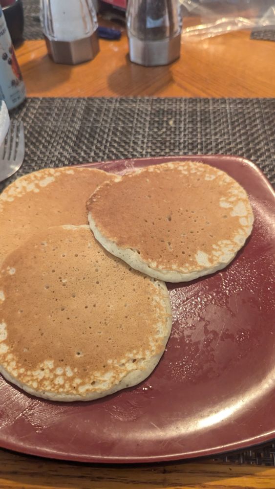 Three perfect pancakes on a red plate.