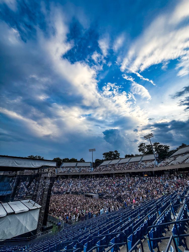 A photo of the crowd and amazing blue sky with dramatic clouds over the Westville Music bowl as King Gizzard & the Lizard Wizard person on stage. 