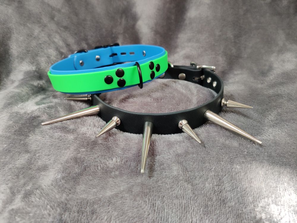 Two collars! Top one has an electric blue base, a neon green overlay, and it's got a black D ring held on the front with six rivets in two triangle patterns. The bottom one is black and spiky: alternating long and short silver spikes, at just over one and two inches long. 