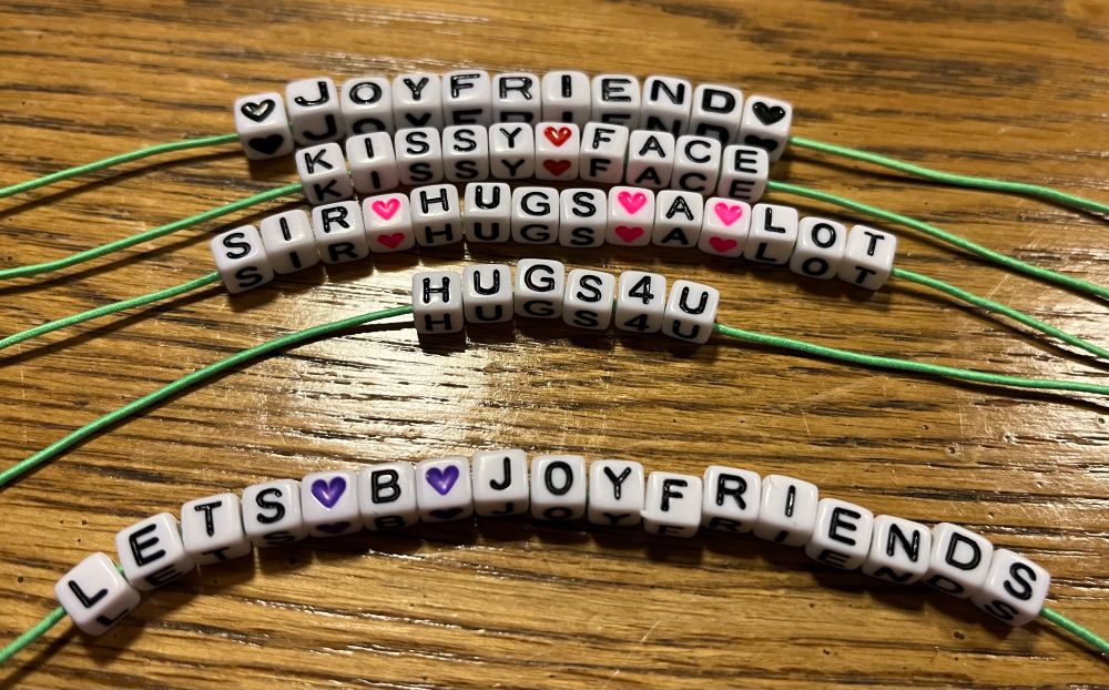 Five untied bracelets, using letter beads to spell out, “joyfriend” kissy face” sir hugs-a-lot” and “let’s be joyfriends”