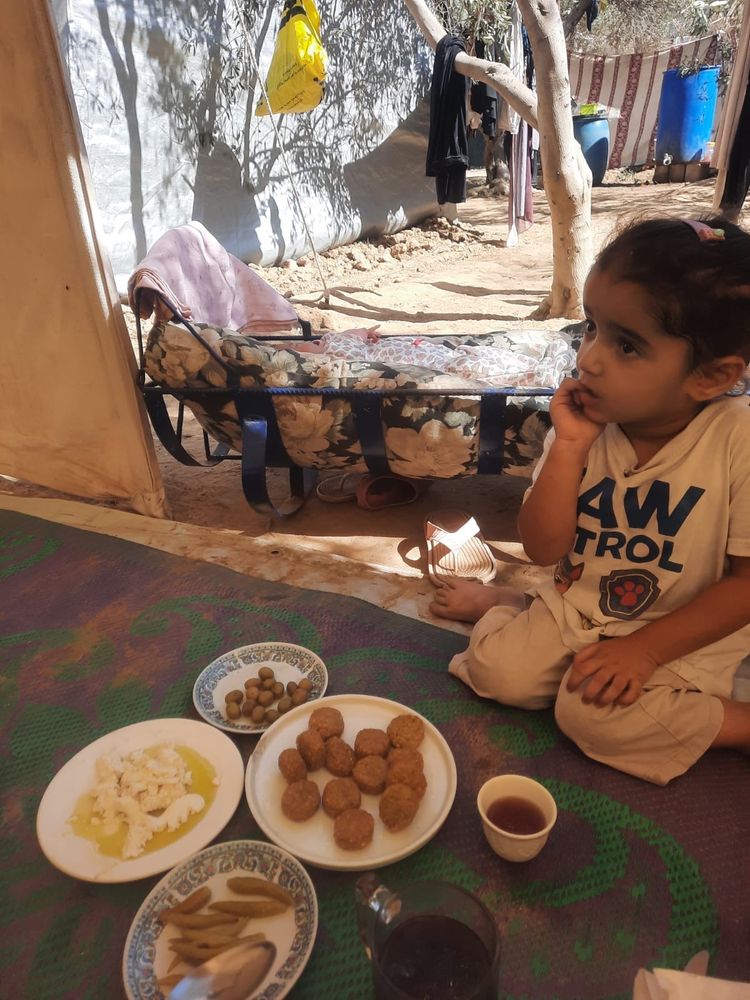 Little Julia in a Paw Patrol shirt snacking on olives, falafel, cheese, and fried potato. There’s a little pitcher of iced tea too.