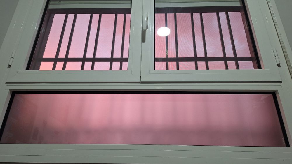 Foto de una ventana por la que se ve el cielo en tonos rosados.