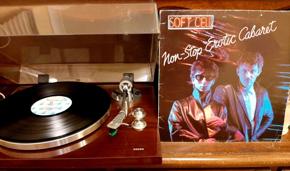 12" black vinyl LP of "Non-Stop Erotic Cabaret" by Soft Cell, on an ION turntable and side-by-side with the outer sleeve. 