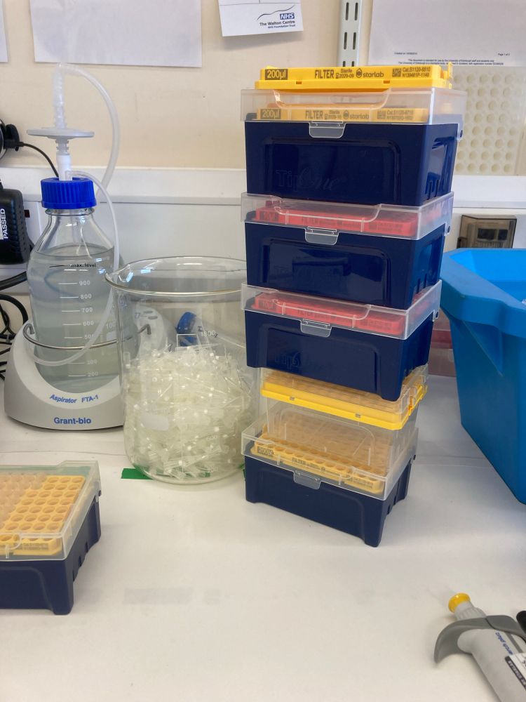 A bucket filled with tips and a big stack of empty pipette tip boxes. 