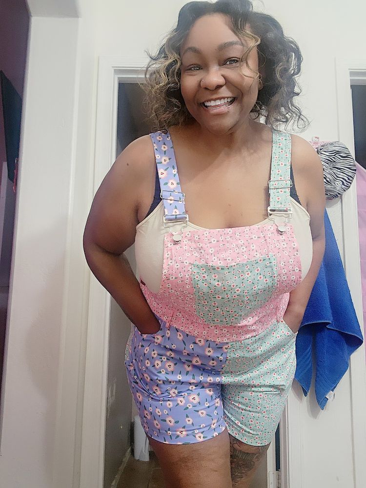 Beautiful black woman in patchwork pastel overall shorts and a taupe tanktop.