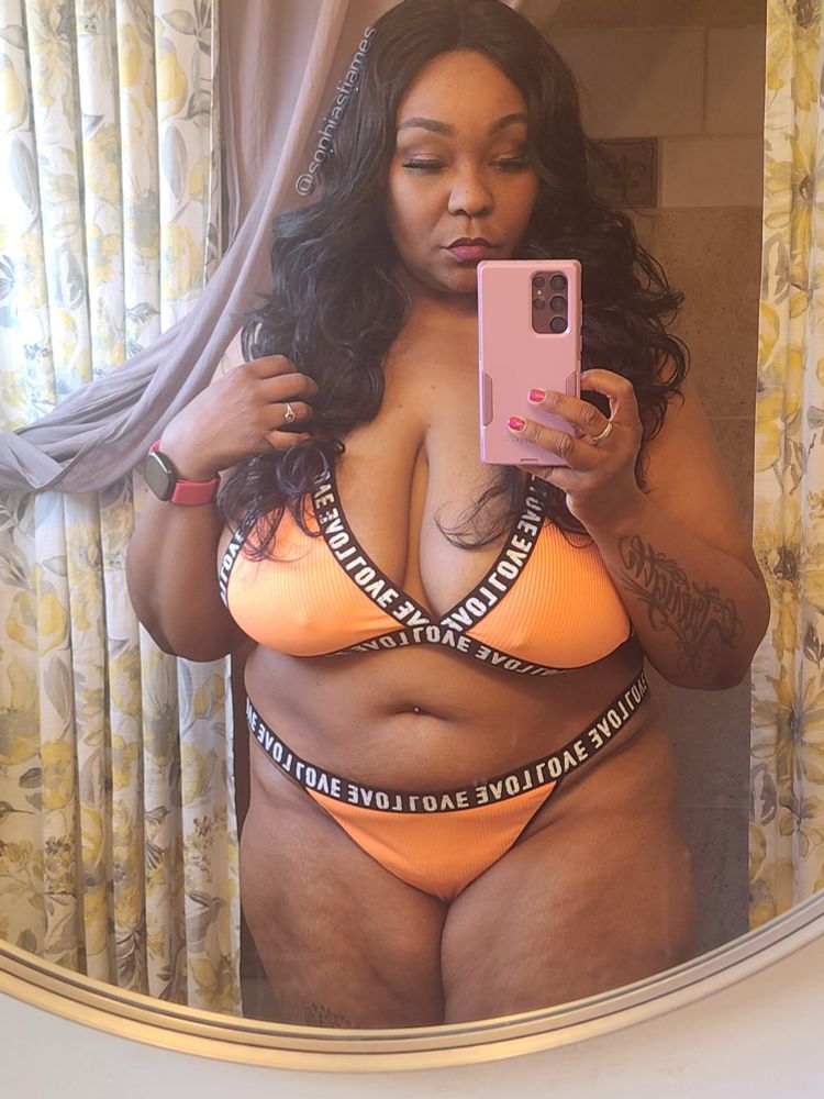 Sophia, a beautiful sexy ebony woman, westing a 2 pc bikini that is orange with black trim. 