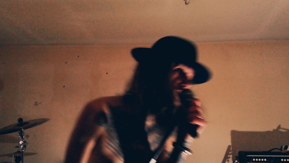 The singer, toeless and in shadow leaning into the mic