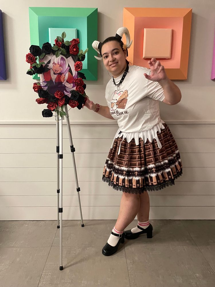 A person is posing next to a custom poster with roses adorning the border