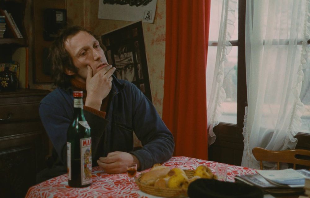 Image extraite du film Un Condé, d'Yves Boisset. On y voit l'acteur Rufus, assis à table dans une position plutôt dubitative.