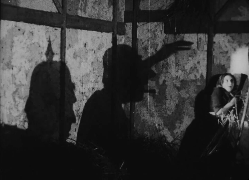 Image extraite du film J'Accuse, d'Abel Gance. On y voit une jeune femme menacée par l'ombre gigantesque de soldats allemands. Une façon d'évoquer les viols de guerre