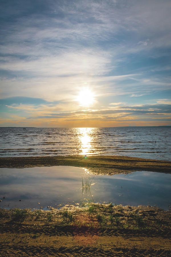 The sun sets over Lake Nipissing in the aptly-named Sunset Park in North Bay, Ontario, lighting up the blue waters and the partly-clouded sky.
