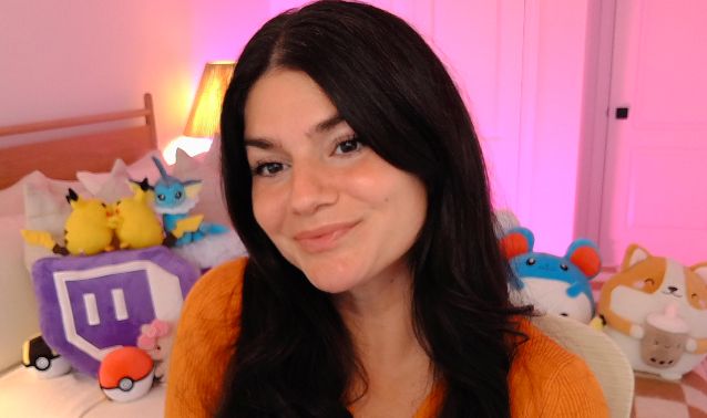 Dark haired girl in orange sweater on pink backdrop 