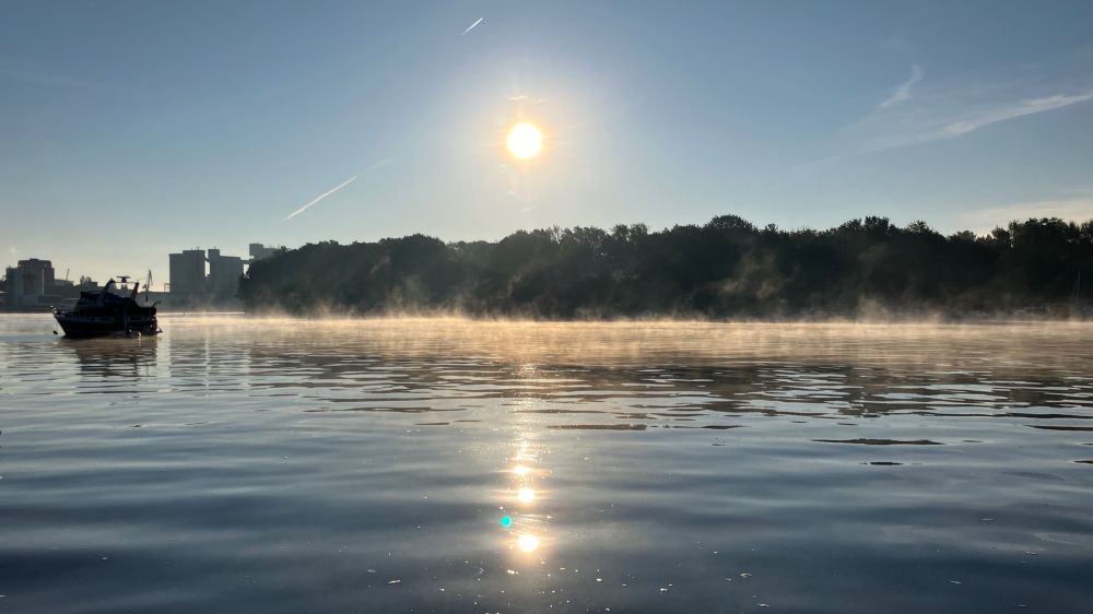 Blick über die Rummelsburger Bucht. Die Morgensonne scheint und spiegelt sich auf dem Wasser. Nebel steigt auf.