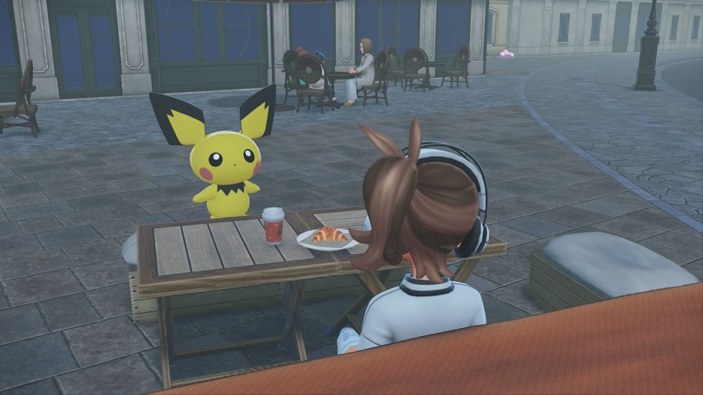 screenshot from Pokémon Legends Z-A. my player character is sitting at a café with a shiny alpha pichu.