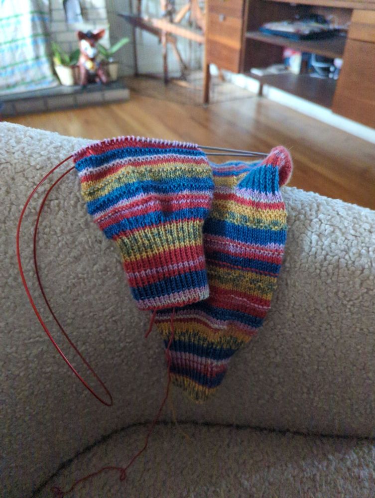 Multi color knitted socks on the arm of a chair 