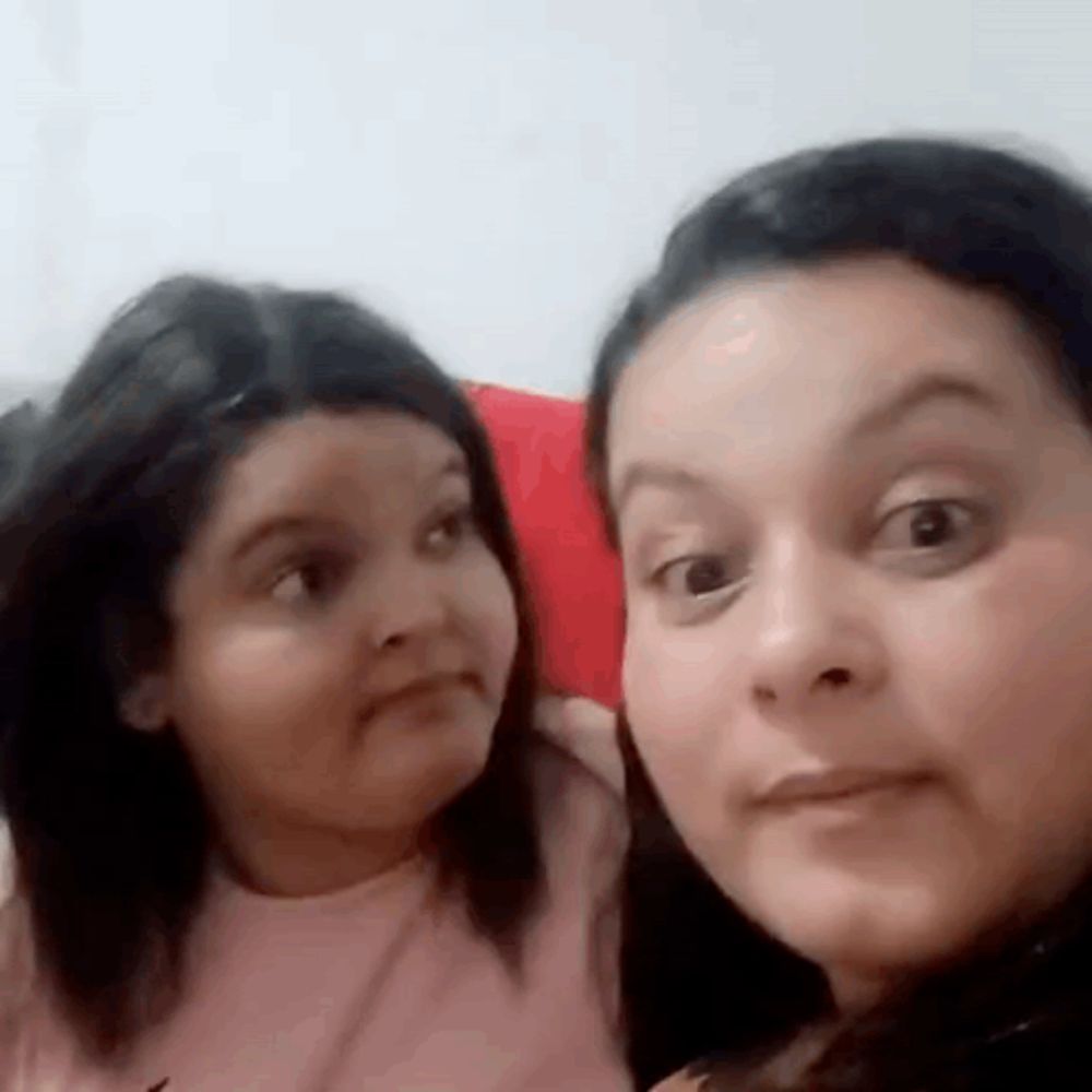 a woman and a little girl are making funny faces while sitting next to each other on a couch .