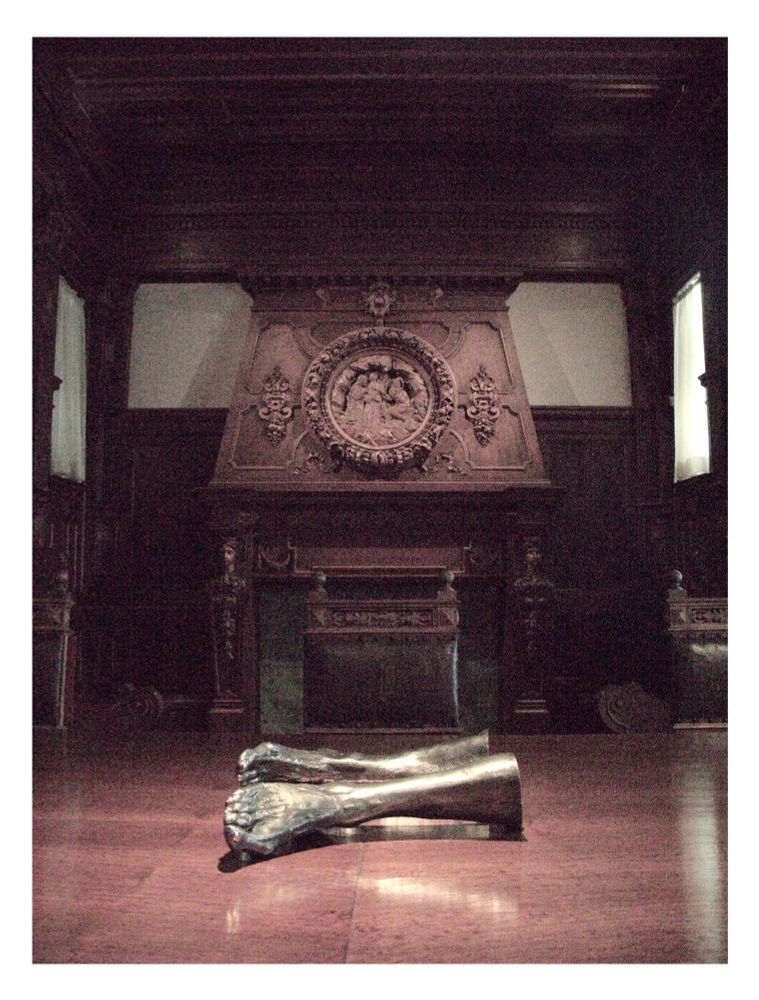 Crossed legs on a large wooden dining table.  Dark lighting.