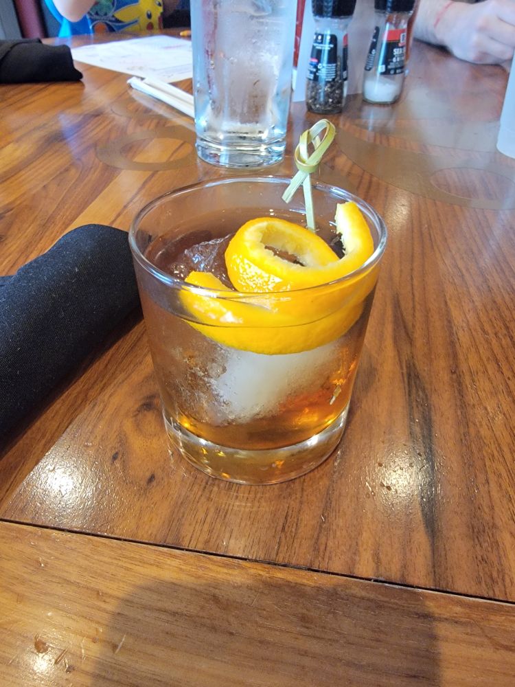 A small cocktail with a spiral of orange peel on top