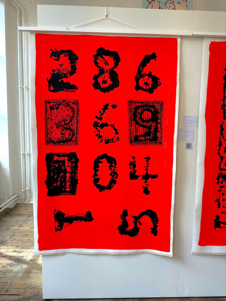 Large red painting with black numbers, three to a line for the first two lines, two numbers in the third and last line. The numbers are 0-9, but out of order and the last two, a one and a five, lying on their side.