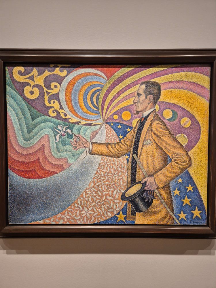 Quadro de Paul Signac no Museu da Arte Moderna em Nova Yorke. O quadro apresenta um homem de terno amarelo, chapéu e bengala. Ele é branco, possui um cavanhaque e cabelos curtos. Ao fundo se vê um papel de parede com uma combinação de cores e formatos com cores de tons fortes