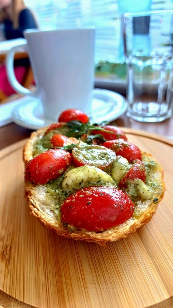 Imagem mostrando um pão torrado com manjericão, queijo, e tomate. 