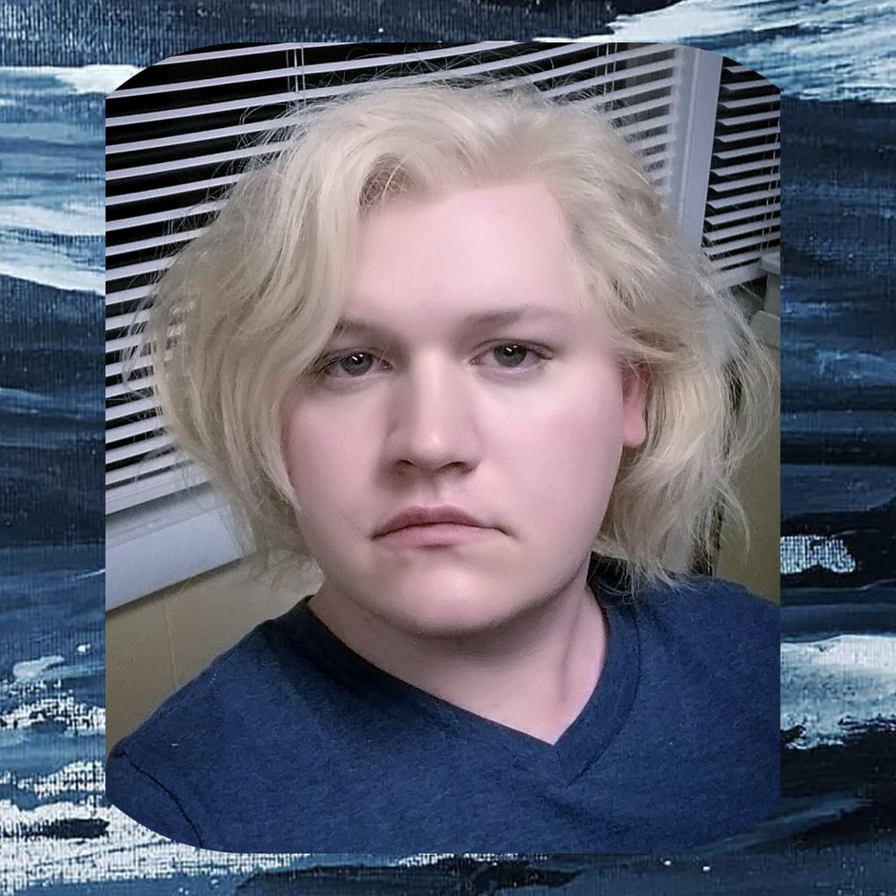 Photo of me wearing a blue shirt with a blue and white boarder. I have blue eyes and platinum blonde hair 