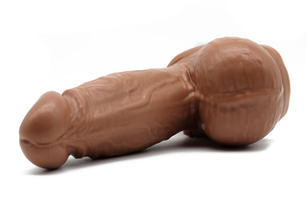 Dutch pictured from below. This realistic dildo has a flared head, a girthy shaft decorated with plump veins, and a fat sack with skin crinkle details.