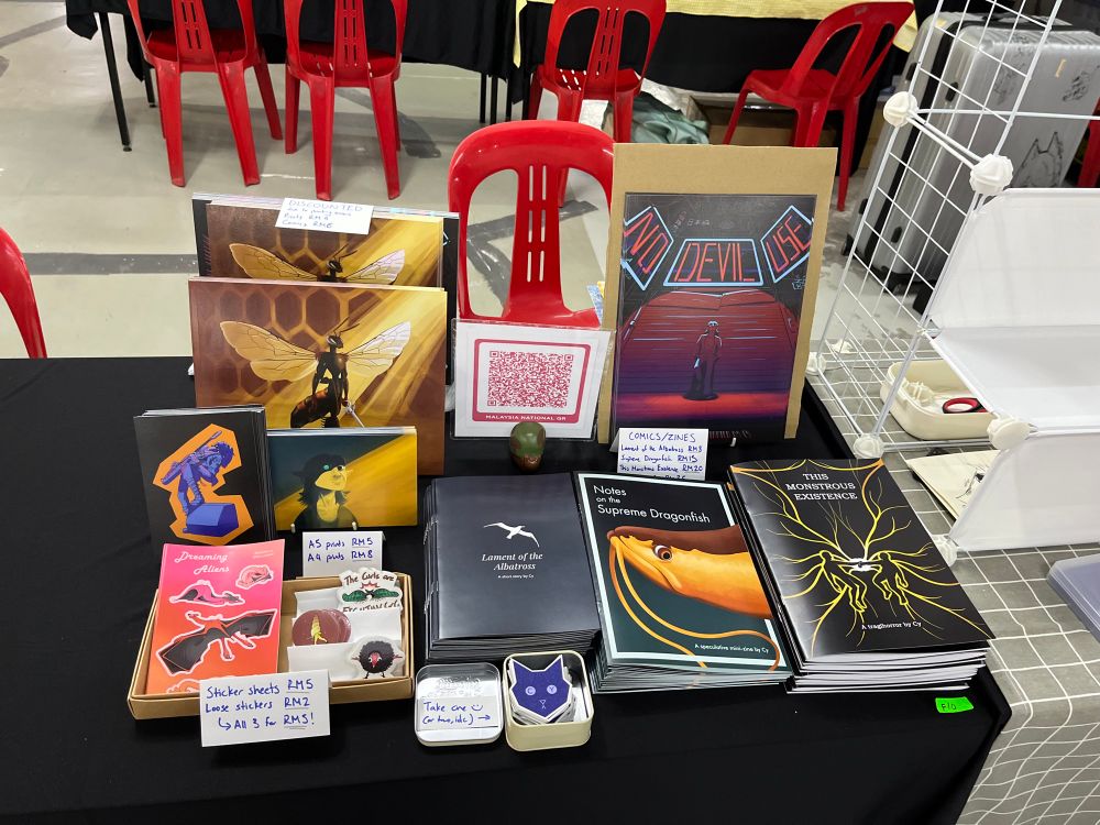 Half-booth with a variety of stickers, prints, and comics/zines.