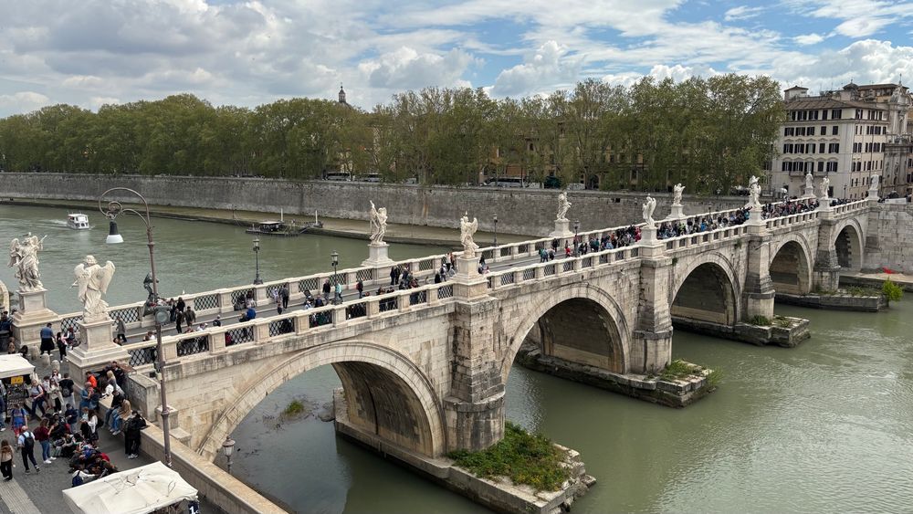 Sant Angelo bridge over Tiber river. White stone bridge lined on both sides with angel statues. 
