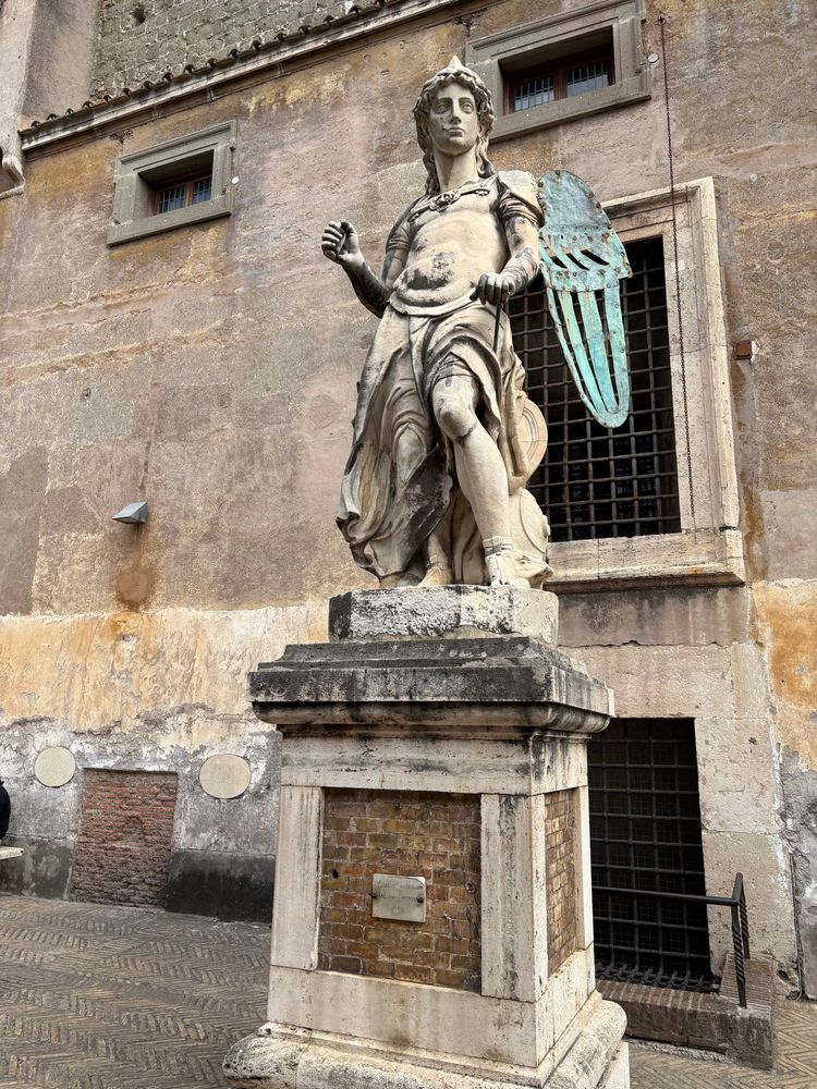 White statue of Archangel Michael with bronze wings inside Castel Sant Angelo in Rome. 