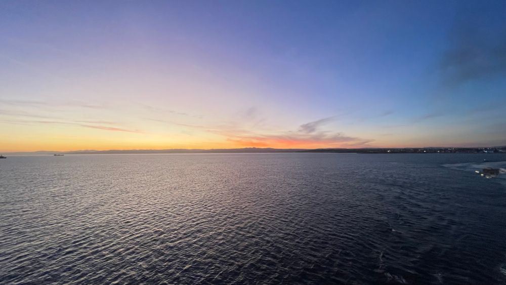 View of Sardinia’s coastline at sunset, across the sea, from a ferry leaving for Corsica